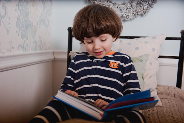 Kleine jongen in pyjama leest een boek voor het slapengaan.