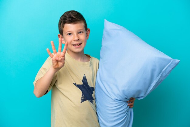 Kleine jongen in pyjama's geïsoleerd op blauwe achtergrond blij en vier tellen met vingers