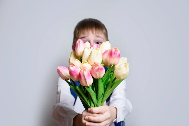 Kleine jongen in wit overhemd met een boeket van tulpen