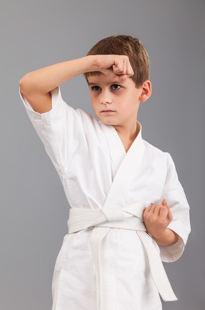 Kleine jongen in witte kimono karate beoefenen