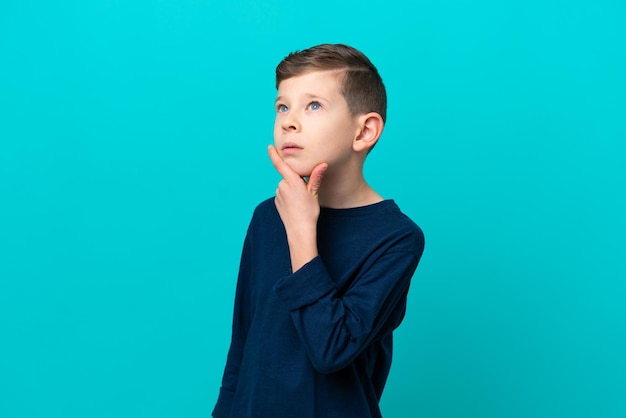 Kleine jongen jongen geïsoleerd op blauwe achtergrond met twijfels