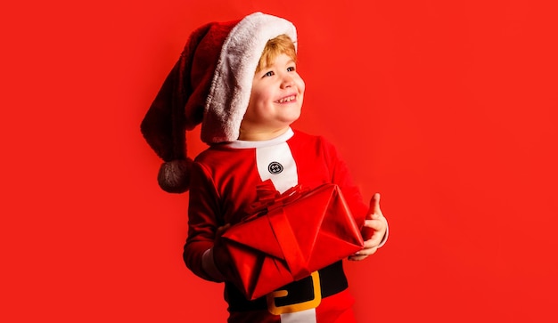 Kleine jongen jongen in kerstmuts met huidige geschenkdoos schattig glimlachend kerstkind gelukkig nieuwjaar