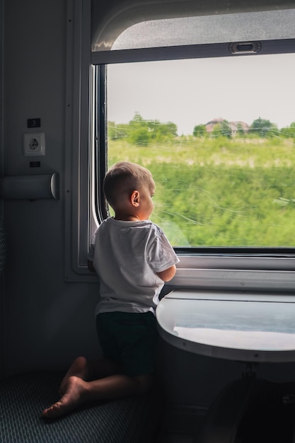 Kleine jongen kijkt uit het raam van de trein