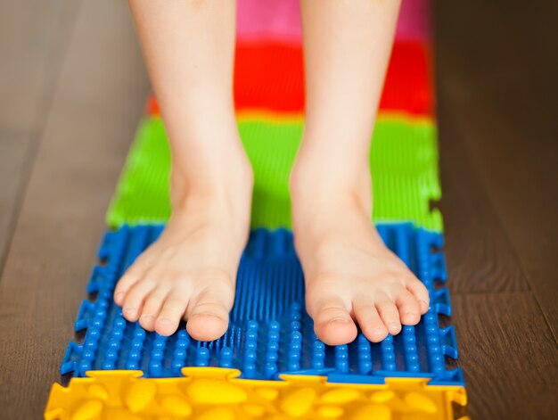 Kleine jongen kind lopen op een orthopedische massagemat. Behandeling en preventie van platvoeten bij kinderen.