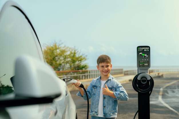 Kleine jongen laadt milieuvriendelijke elektrische auto op vanaf EV-laadstation EV-auto-roadtrip langs de kust met een alternatief voertuig aangedreven door schone hernieuwbare en duurzame energie Perpetual