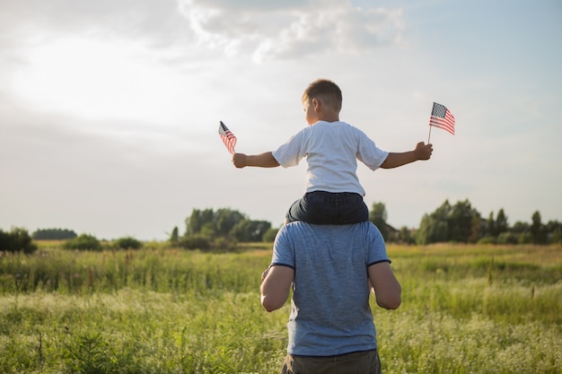 Kleine jongen laat de Amerikaanse vlag in zijn handen vliegen op de wind op het groene veld