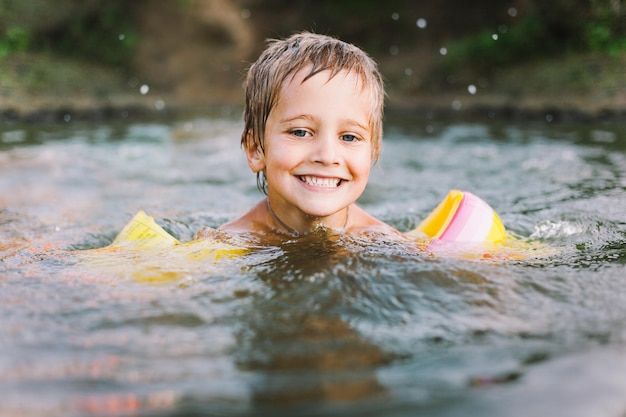 Kleine jongen lacht en zwemt in de rivier op hete zomerdag Soft focus Horizontale opname