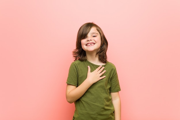 Kleine jongen lacht hardop terwijl hij de hand op de borst houdt.