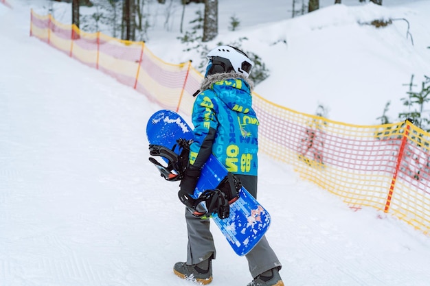 Kleine jongen leren rijden op snowboard staande op skipiste Winter vrije tijd