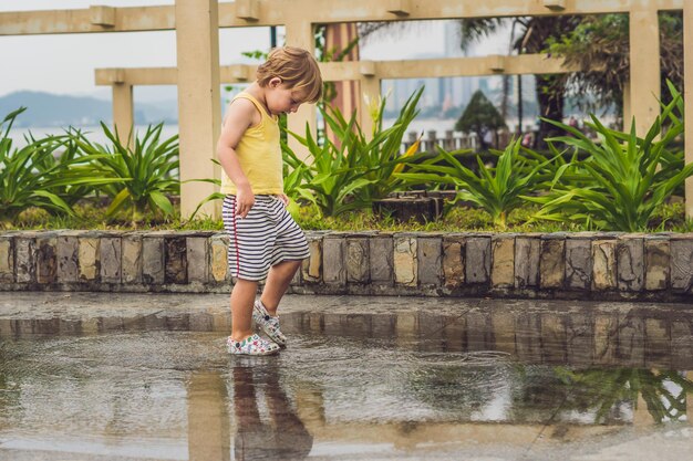 Kleine jongen loopt door een plas. zomer buiten.