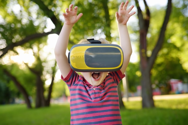 Kleine jongen met behulp van virtual reality headset buiten. VR, VR-bril, augmented reality-ervaring.