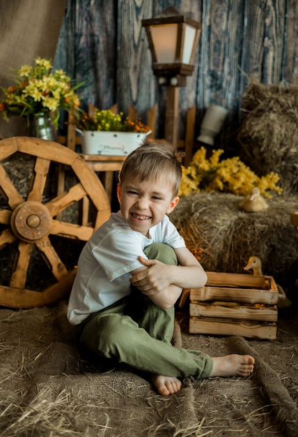 Kleine jongen met bruin haar lachen zit op een rietje in een rustieke stijl