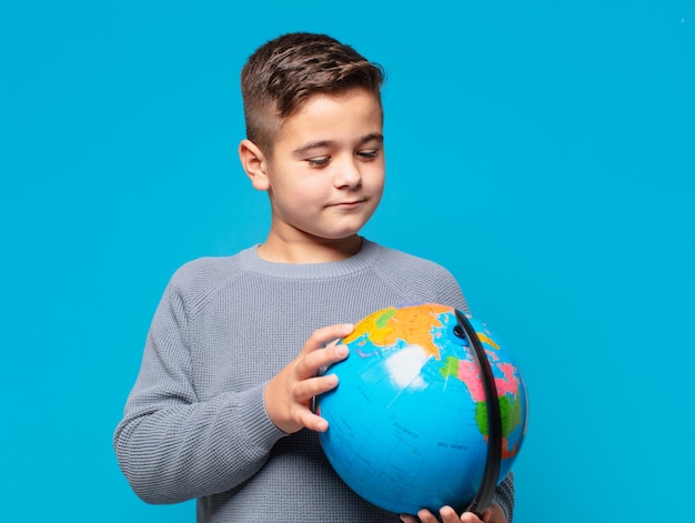 Kleine jongen met denkexpressie en een wereldkaartmodel vast te houden