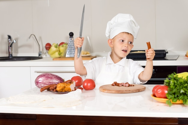Kleine jongen met een groot mes in de keuken
