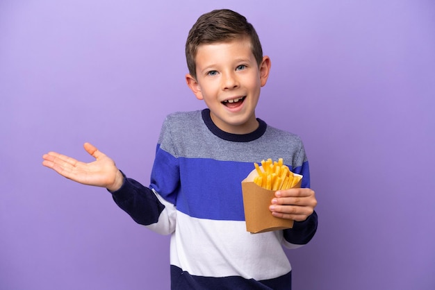 Kleine jongen met gebakken chips geïsoleerd op paarse achtergrond met geschokte gezichtsuitdrukking