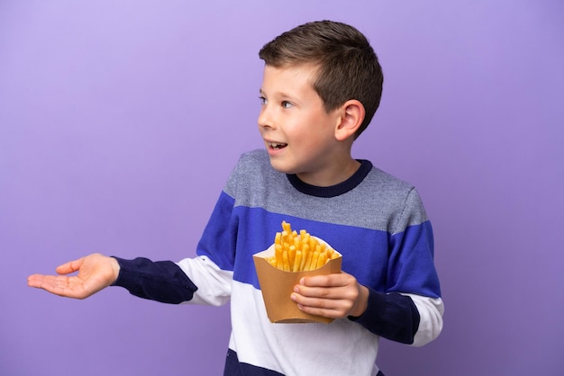 Kleine jongen met gebakken chips geïsoleerd op paarse achtergrond met verrassingsuitdrukking terwijl hij opzij kijkt