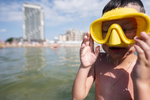 Kleine jongen met geel duikmasker en zwembril op het strand