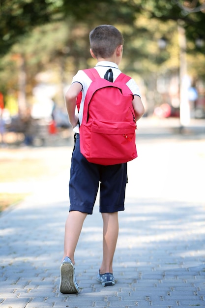 Kleine jongen met grote schooltas buiten