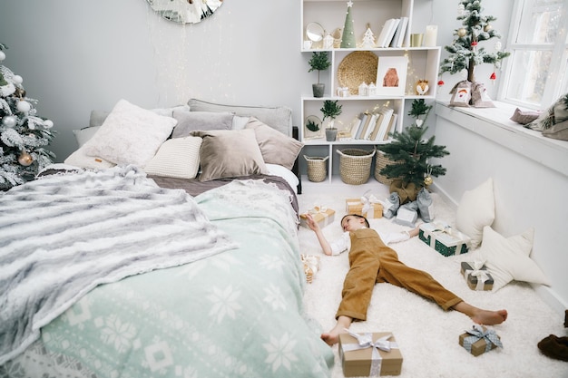 Kleine jongen met kerstcadeaus op de grond liggen