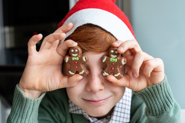 Kleine jongen met kerstmuts en plaat van koekjes