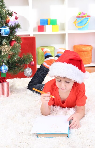 Kleine jongen met kerstmuts schrijft brief aan de kerstman