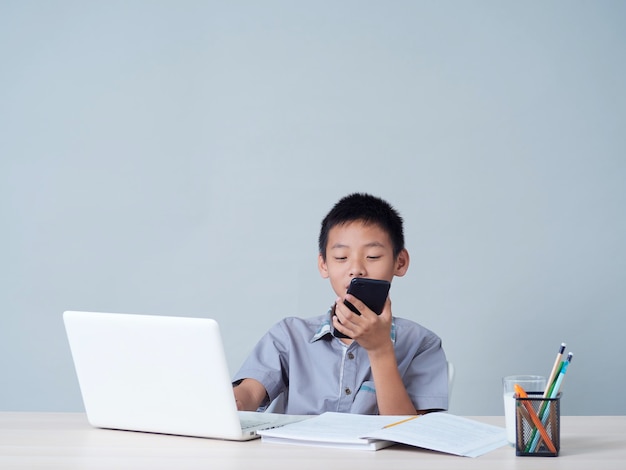 Kleine jongen met laptop die online studeert