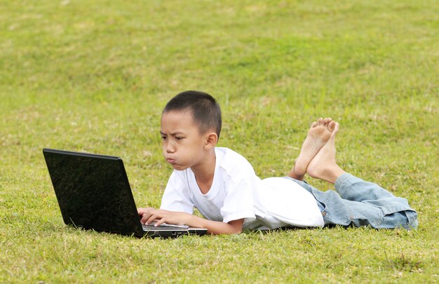 Kleine jongen met laptop op het gras