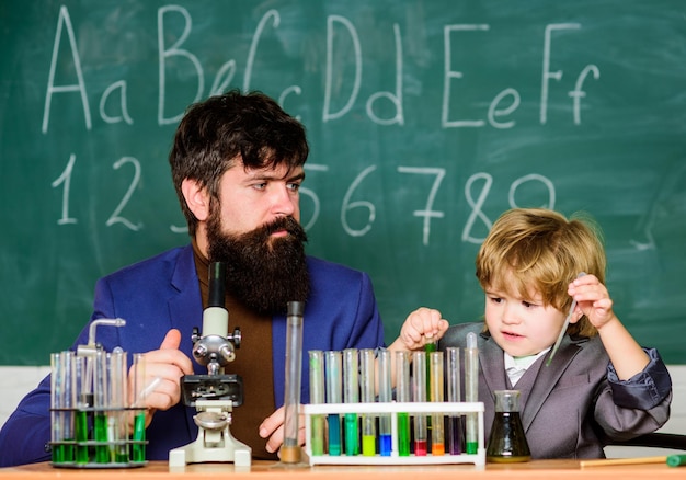 Kleine jongen met leraar man Terug naar school zoon en vader op school Moderne laboratoriumbioloog voert experimenten uit door verbindingen te synthetiseren Innovatie is de sleutel tot alles wat de toekomst kan zijn