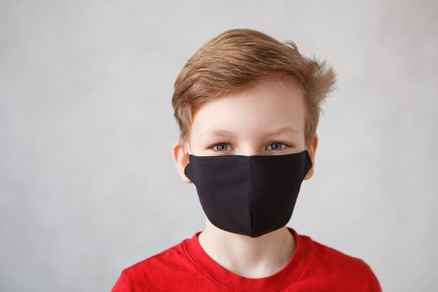 Kleine jongen met masker tegen het coronavirus covid-19, 2019-nCov. Kind in een chirurgisch verband of gasmasker tijdens het coronavirus