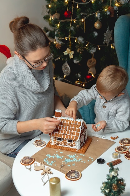 Kleine jongen met moeder versieren kerst peperkoek huis samen