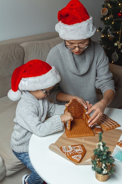 Kleine jongen met moeder versieren kerst peperkoek huis samen