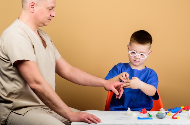 Kleine jongen met vader in het ziekenhuis. vader en zoon in medisch uniform. gelukkig kind met vader met stethoscoop. huisarts. geneeskunde en gezondheid. ziekenhuis concept. familie in het ziekenhuis.