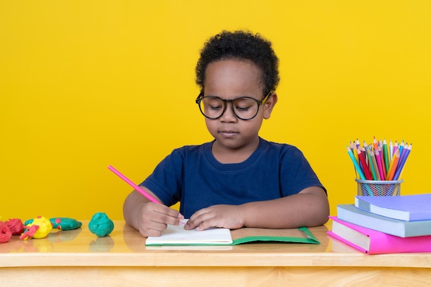 Kleine jongen met verbeeldingskracht Zittend aan tafel tekenen met kleurpotloden