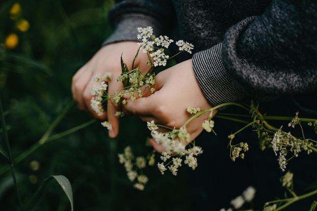 Kleine jongen met wilde bloemen in zijn handen in de zomer