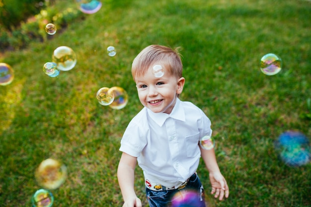 Kleine jongen met zeepbellen in zomer park.