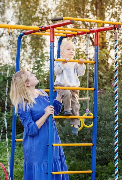 Kleine jongen met zijn moeder op speelplaats op zomerdag