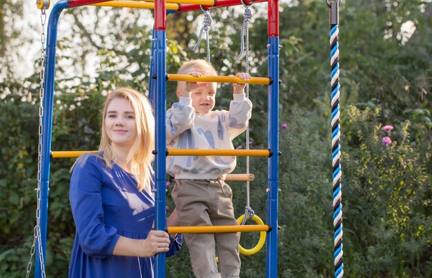 Kleine jongen met zijn moeder op speelplaats op zomerdag