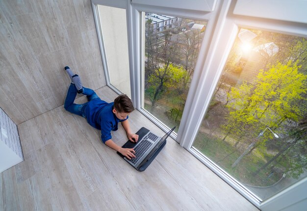 Kleine jongen ontspannen op een terras en surfen op het net op slimme telefoon