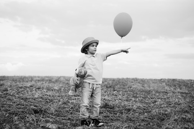 Kleine jongen op de landelijke weg tussen het gekleurde veld wijzend op een copyspace de schattige jongen i