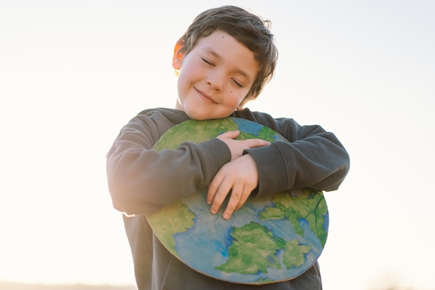 Kleine jongen planeet in handen houden tegen groene lente achtergrond aarde dag