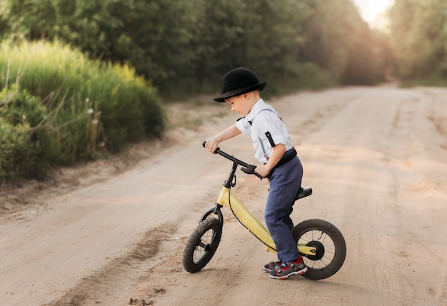 Kleine jongen rijdt in de zomer op een loopfiets in de natuur. Run fiets zonder pedalen