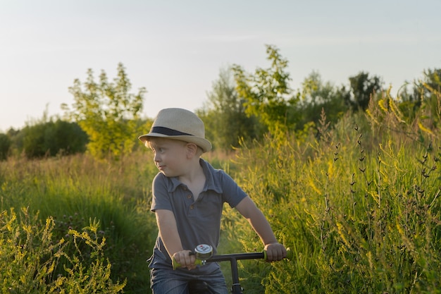 kleine jongen rijdt op een loopfiets Zomeractiviteit van het concept van fysieke activiteit op het platteland