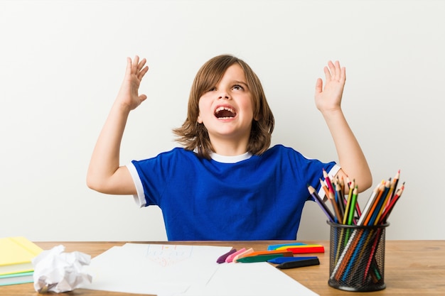 Kleine jongen schilderen en huiswerk op zijn bureau schreeuwen naar de hemel.