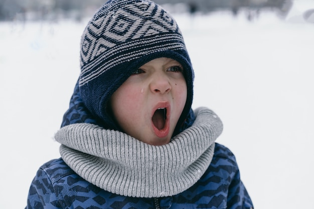 Kleine jongen schreeuwt en huilt. Emoties. Jongen in de winterkleren