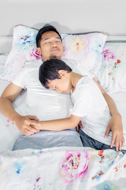Kleine jongen slaapt vredig met zijn vader op bed