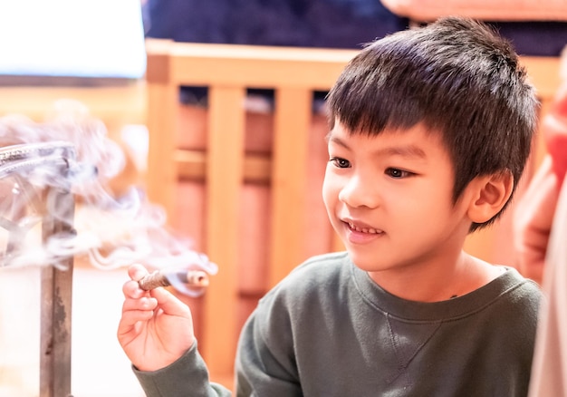 Kleine jongen speelt gevaarlijk met brandend hout in een houten huis voor kinderen gevaar spelen met vuur concept