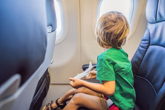Kleine jongen speelt met speelgoedvliegtuig in het commerciële straalvliegtuig dat op vakantie vliegt