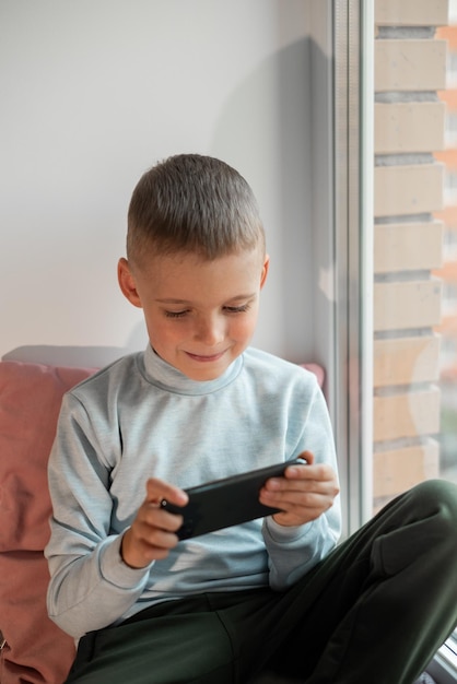 Kleine jongen speelt mobiel spel op smartphone zittend op een bank bovenaanzicht Kind vrije tijd thuis video