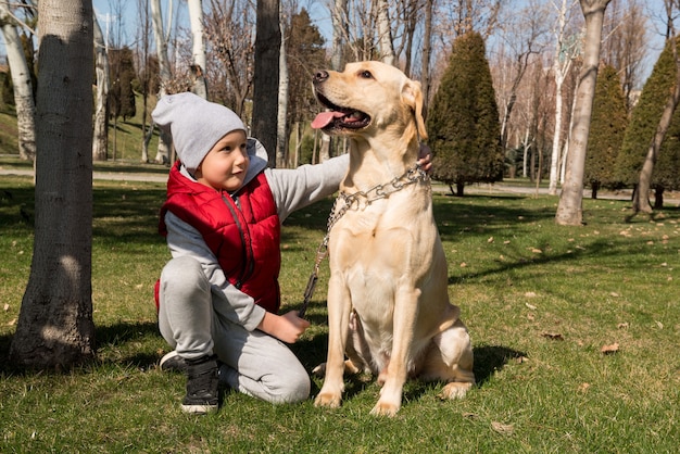 Kleine jongen spelen met hond labrador in lente park