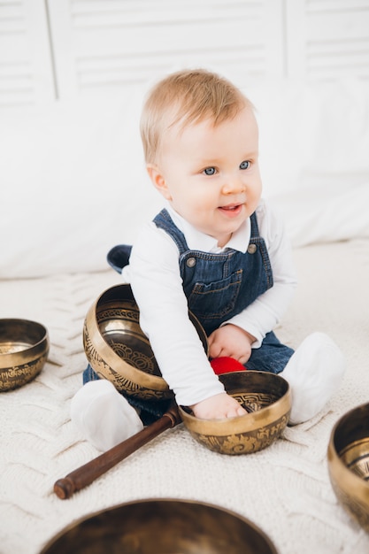 Kleine jongen spelen met Tibetaanse klankschalen zittend op het bed